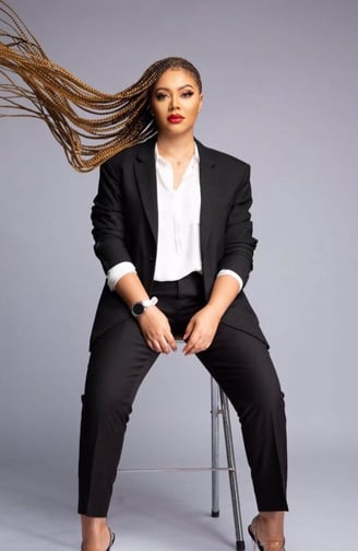 Nadia Buari in a black top and trousers with a white inner shirt.