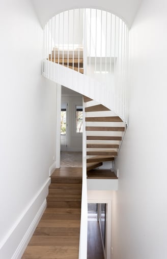 Minimalist interior featuring metal spiral staircase with timber treads, white walls, clean design