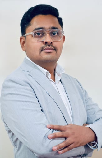 a man in a suit and glasses with a white shirt. Prajwal R Basavaraju founder of The Evolving Man
