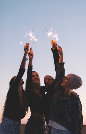 a group of friends holding sparklers in the sky
