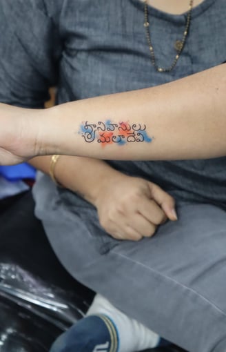 Name tattoo with orange and blue watercolor effect on hand by Dudo’s Hyderabad