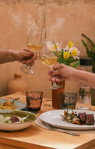 Dos copas brindan la comida que han pedido Es Mestral, se trata de solomillo, pescado fresco y unas alcachofas