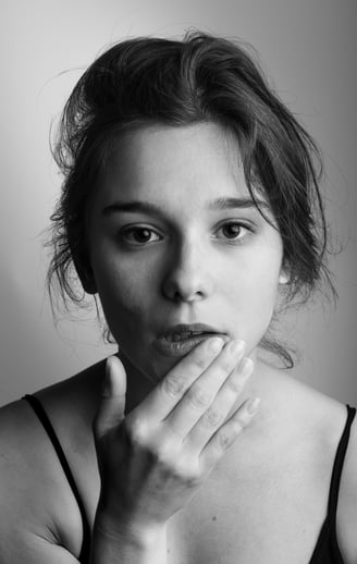 une femme la main au visage sous les levres