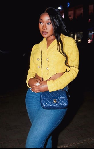 Efia Odo in a yellow top and a black jeans trousers strapped with a Coco Chanel bag.