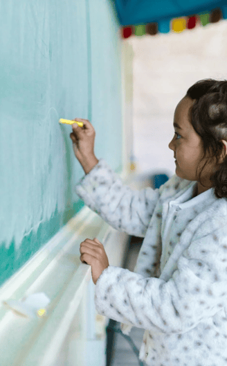 A girl writes on a chalkboard.