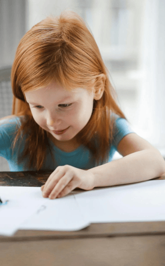 A little girl draws and writes at home.
