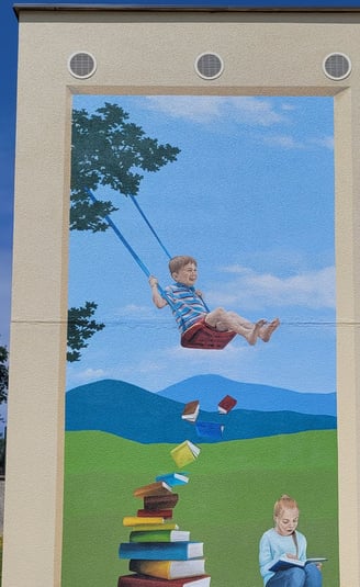 Fresque sur façade. Comme une ouverture dans un mur avec fond paysagé où des enfants jouent.