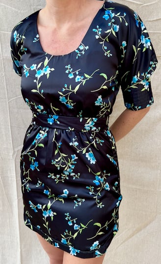 The front of a black satin cocktail dress with blue printed flowers