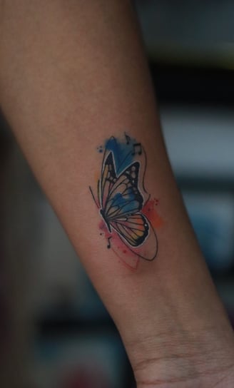 Butterfly tattoo with music notes watercolor fill on arm by Dudo’s Hyderabad