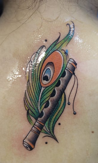 Flute with peacock feather watercolor fill by Dudo's Tattoos Hyderabad