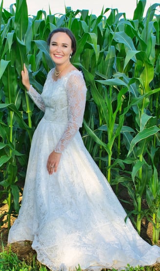 a woman in a white dress standing in front of a corn field