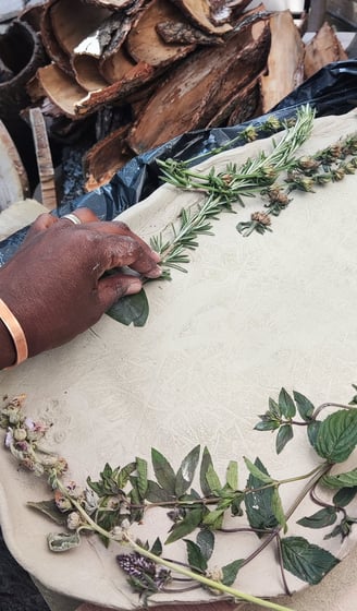 a person pressing a piece of rosemary in to clay