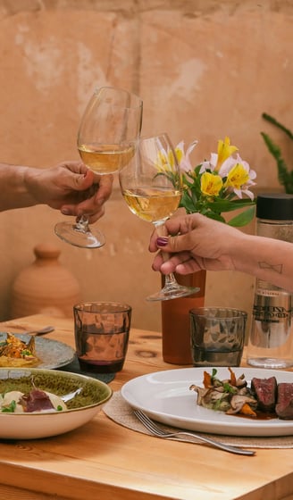Dos copas brindan la comida que han pedido Es Mestral, se trata de solomillo, pescado fresco y unas alcachofas