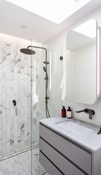 Contemporary bathroom interior with a grey vanity, mirrored wall cabinet, glass-enclosed shower