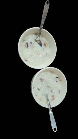 alt="Traditional Kheer served in a bowl with a spoon, containing rice, almonds, raisins, and saffron