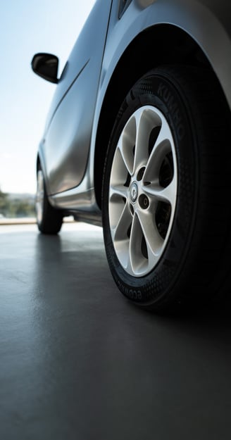 Close-up of a SMART car wheel and side panel on a showroom floor, By ACAT Photos