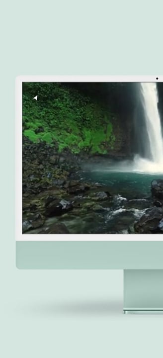 a desktop computer monitor with a waterfall in the background