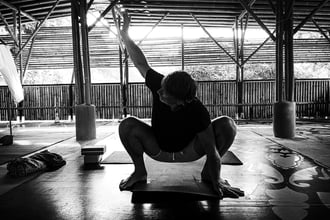 A man executes a squat during yoga class.