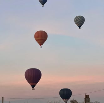 Colorful hot air balloons flying over the desert landscapes near Marrakech at sunrise