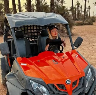 Woman posing behind the wheel of a buggy in the palm grove of Marrakech during an excursion