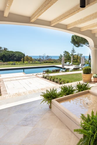 View from the shaded porch across the pool, with the Mediterranean Sea visible in the background.
