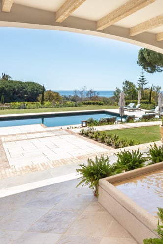 View from the shaded porch across the pool, with the Mediterranean Sea visible in the background.