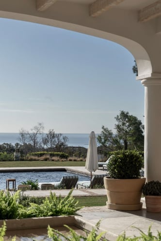 View from the shaded porch across the pool, with the Mediterranean Sea visible in the background.