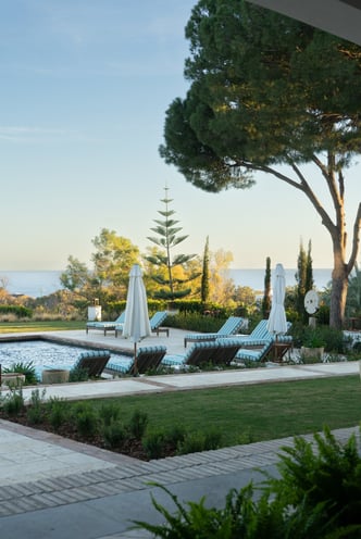 View from the shaded porch across the pool, with the Mediterranean Sea visible in the background.