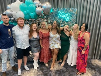 Felisha and 7 friends posing in front of the silver shimmer photo wall she hired in Logan for her 30th birthday.