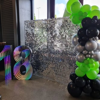 Silver shimmer wall with a green and black balloon garland and 18 marquee number in Eagleby.