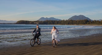 a bride and groom riding bicycles on the beach