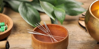 Des aiguilles d'acupunctures dans un bol en bois