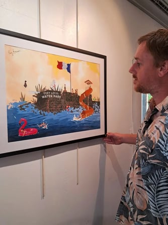 Artist closely examining a framed digital illustration of a water park scene "Splashback"