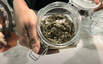 a person holding a jar of mugwort herb