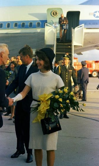 a man and woman shaking hands in front of a plane