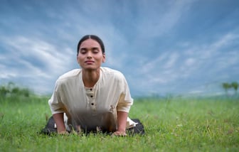 a woman doing Yoga on a grassy field