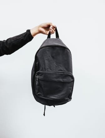 a person holding a black backpack in the air