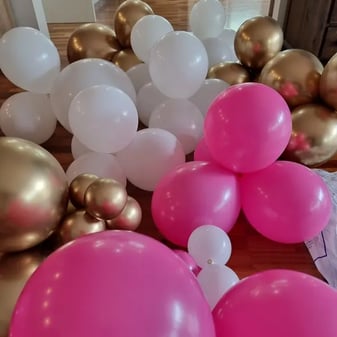 Pink white and gold balloons over the floor in preparation for constructing her balloon garland.
