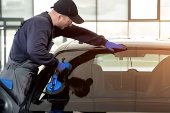 a man cleaning a car with a blue glove
