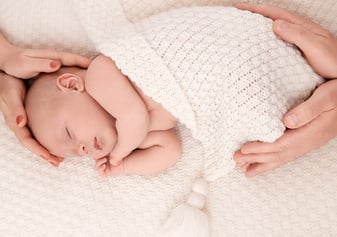 photo de bébé doucement enveloppé des mains de ses parents