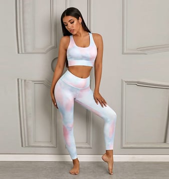 a woman in a pink and blue tie dye yoga outfit