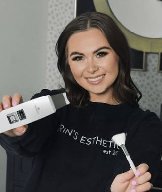 A beautiful woman smiling while holding a skin care tool