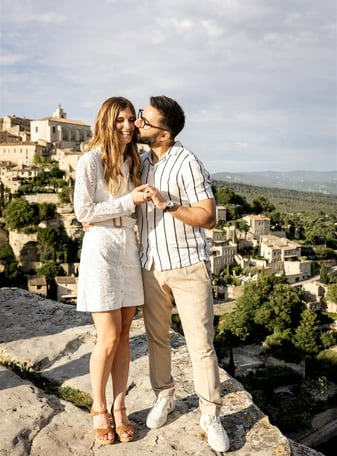 Groom kissing bride on cheek with scenic view of Gordes — South of France wedding photography cost