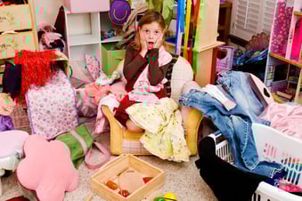 a girl sitting on a chair in a messy room