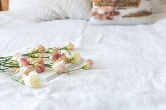 a cake with flowers on a bed in a bedroom