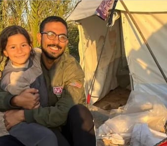 a man and a little girl are sitting in front of a tent