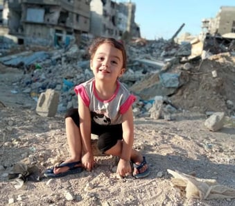 a young girl sitting on a pile of rubble