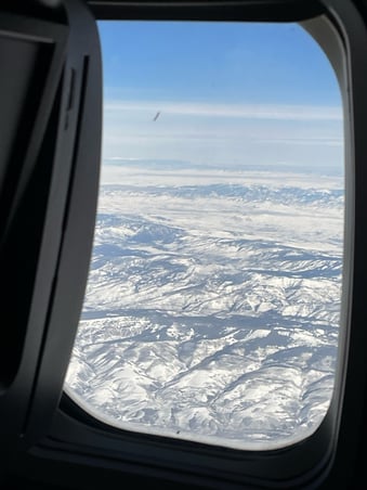 a view of a plane window looking out over a snowy landscape