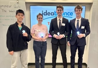 a group of four people holding lightbulbs in front of an ideabounce sign