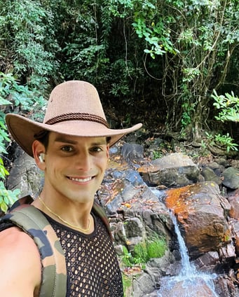 Rick Rockefeller-Silvia with a safari hat, smiling in front of a waterfall in Phuket, Thailand